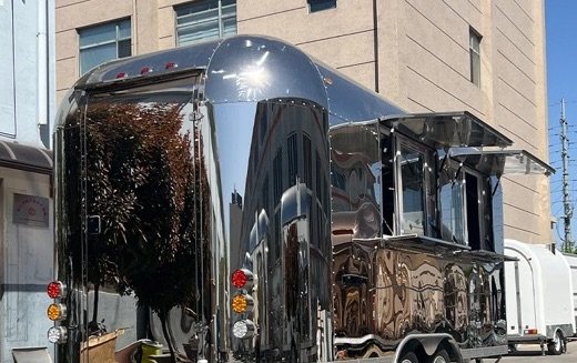 Polished stainless kitchen trailer with service windows open